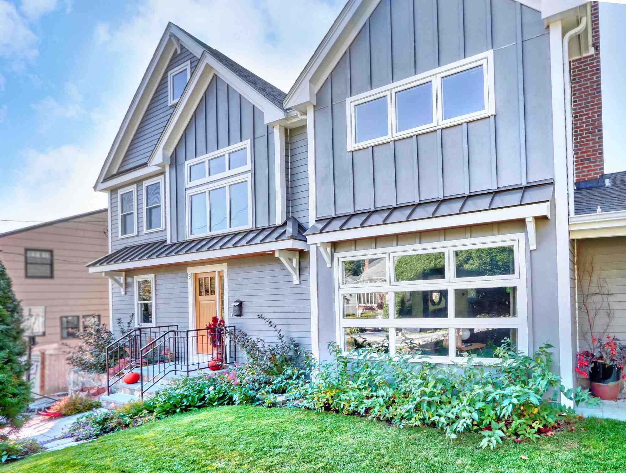 Front exterior home addition in Arlington, MA by Pegasus Design-to-Build with gray siding, large windows, and entryway landscaping-optimized-optimized