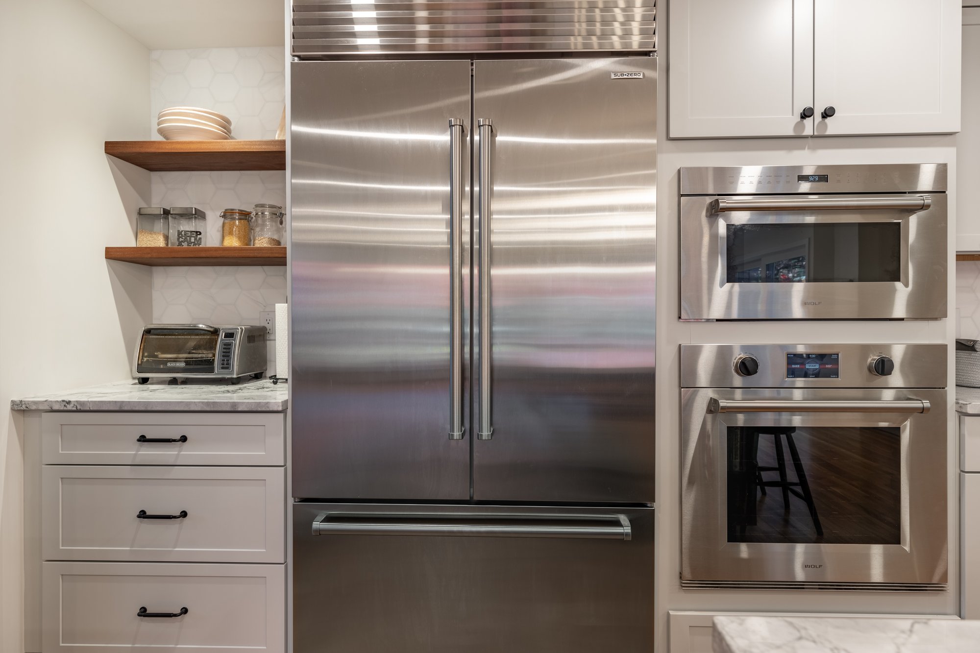 Stainless steel fridge, oven, microwave, and floating shelves in kitchen remodel in Winchester, MA, by PEGASUS Design-To-Build
