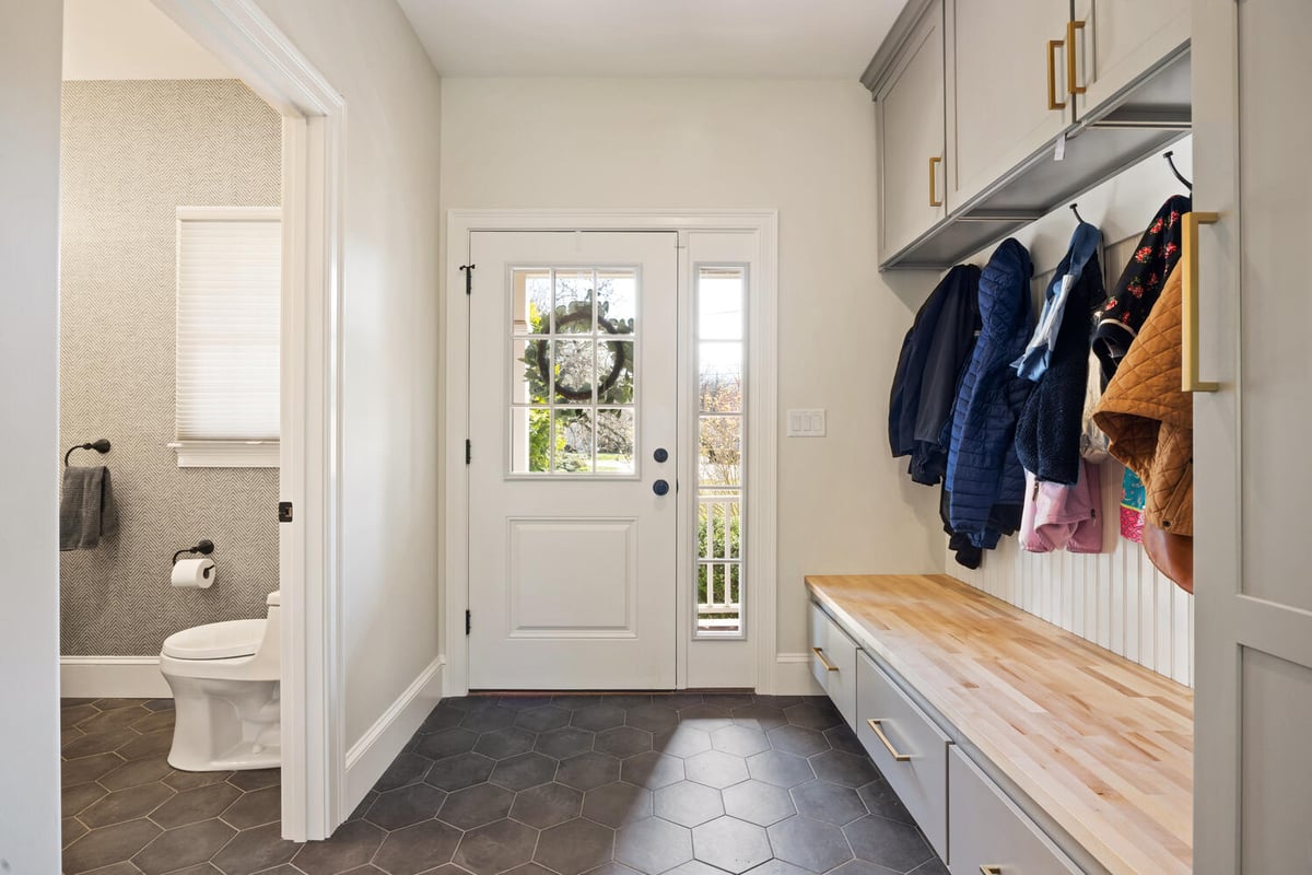mudroom entry with built-in bench and adjacent bathroom by PEGASUS Design-to-Build in Lexington, MA