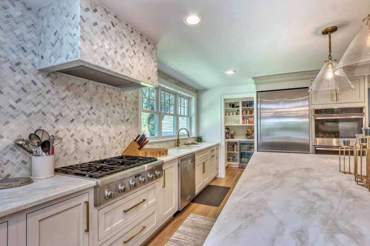 High-end kitchen remodel in Melrose, MA by PEGASUS Design-to-Build with marble backsplash, gas range, and custom cabinetry.-optimized