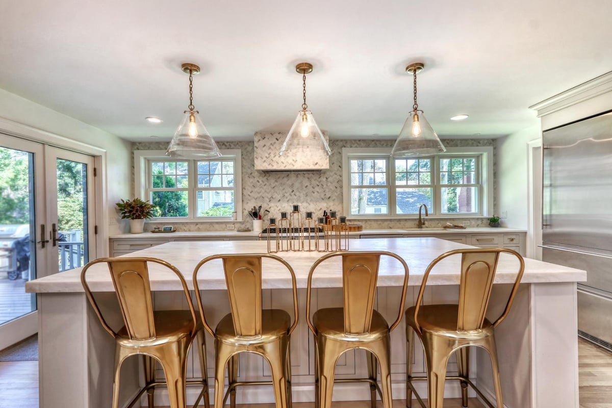 Kitchen island seating area in Melrose, MA by PEGASUS Design-to-Build with brass stools and marble countertops.-optimized