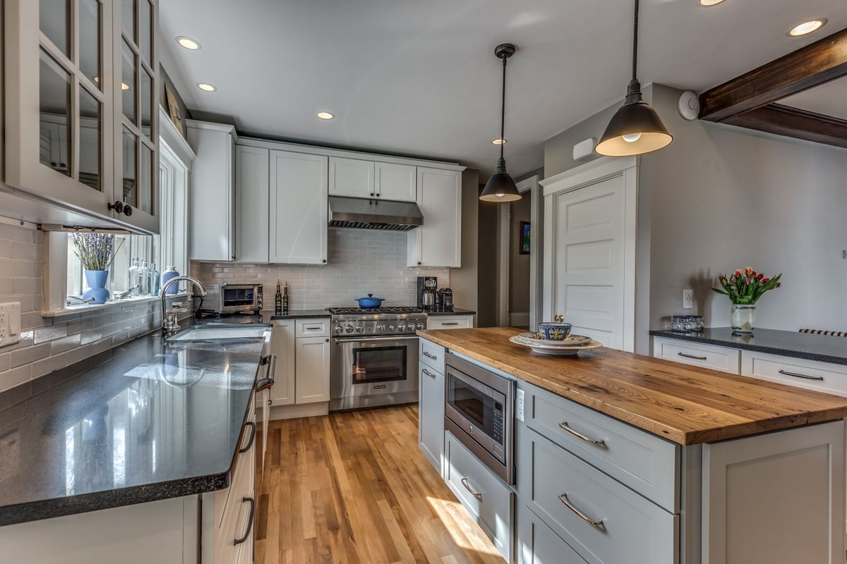 Spacious kitchen renovation in Melrose MA by PEGASUS Design-to-Build with white cabinets, gas range, and wood island-optimized