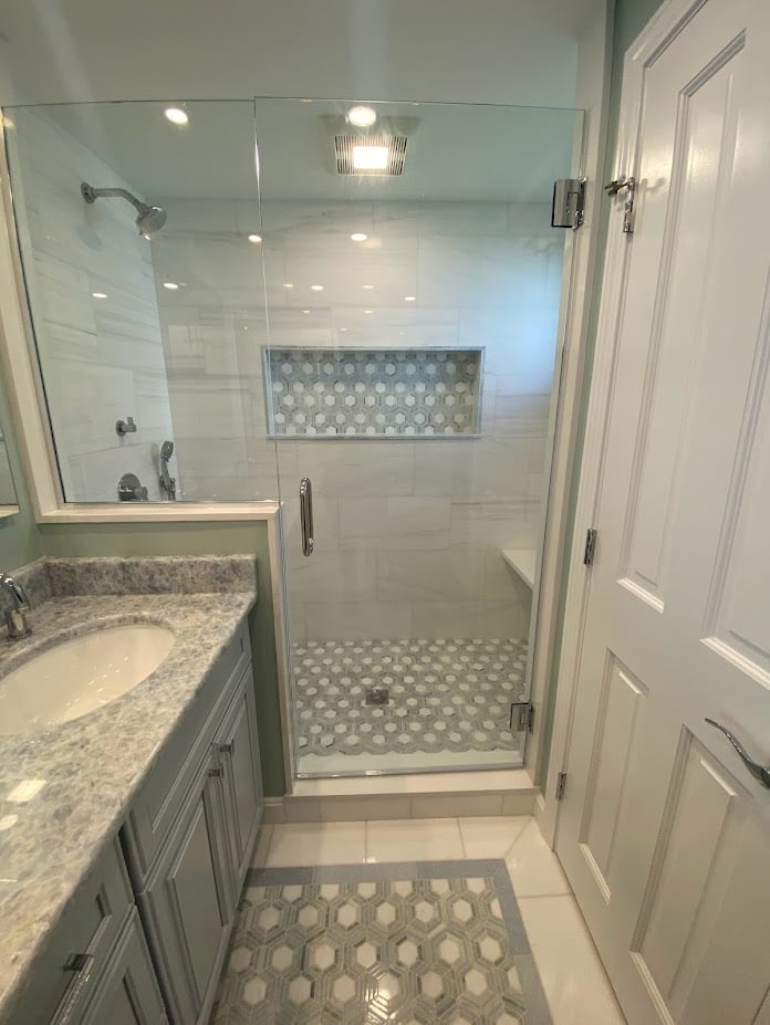 sleek walk-in shower with niche and marble vanity in Melrose MA bathroom renovation by PEGASUS Design-to-Build