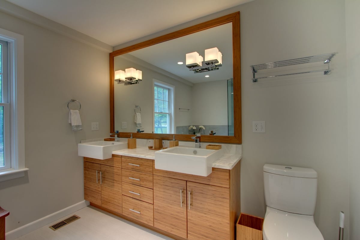 Double vanity bathroom remodel in North Shore MA by PEGASUS Design-to-Build with wood cabinetry and large mirror-optimized