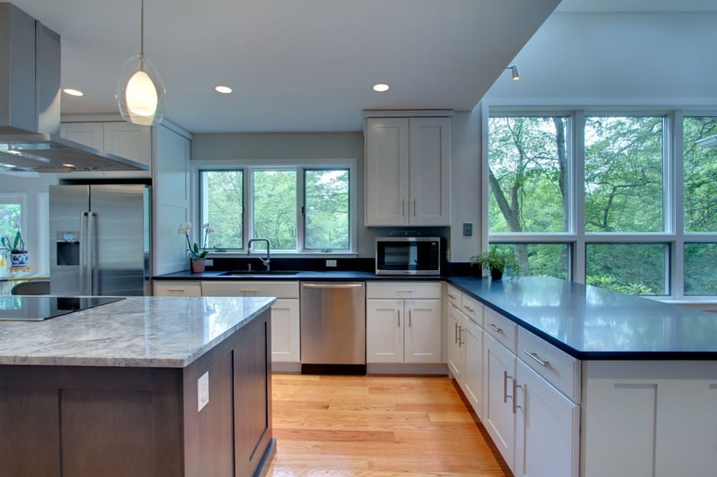Modern kitchen in North Shore MA by PEGASUS Design-to-Build featuring black countertops, white cabinets, and large windows-optimized