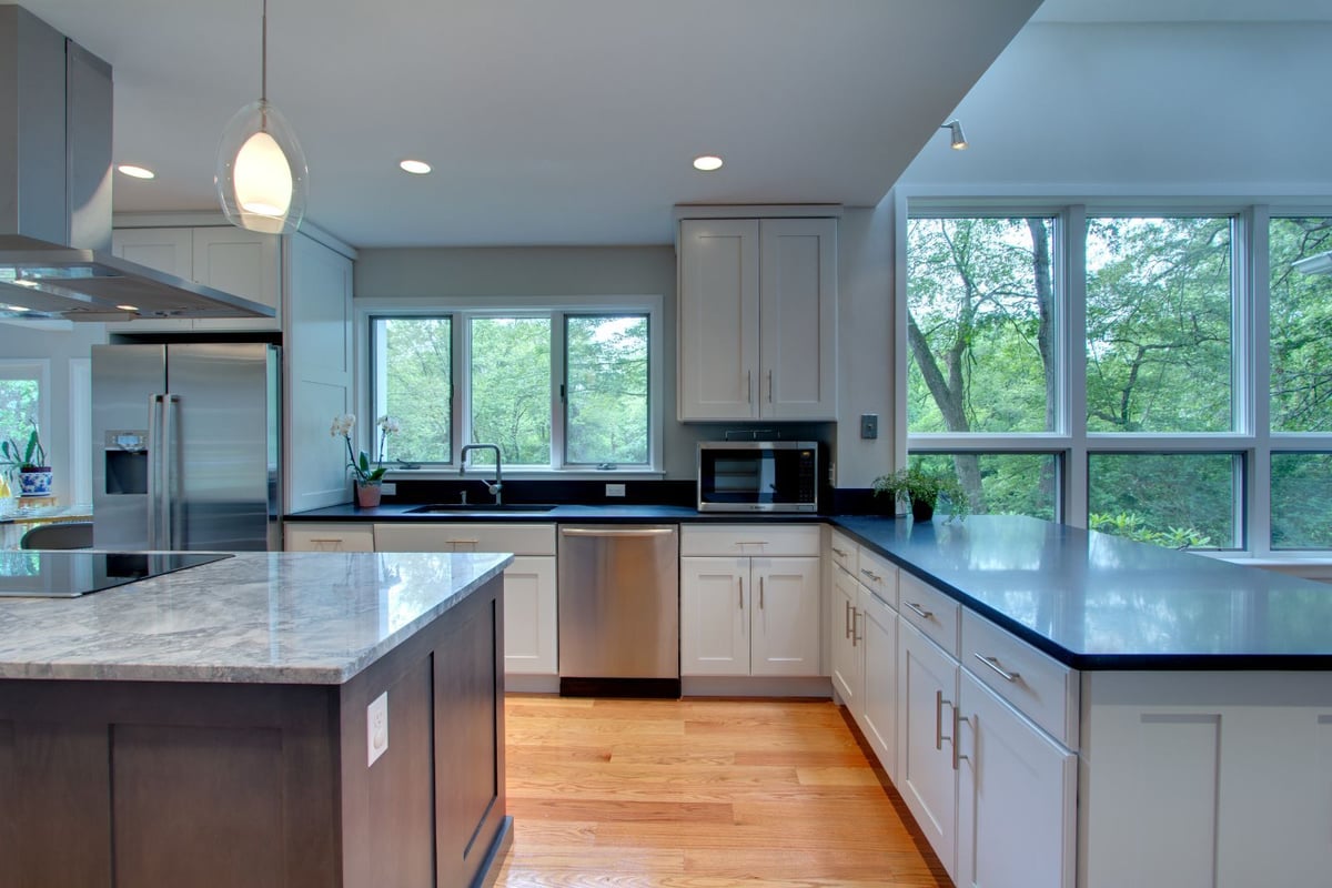 Modern kitchen in North Shore MA by PEGASUS Design-to-Build featuring black countertops, white cabinets, and large windows-optimized