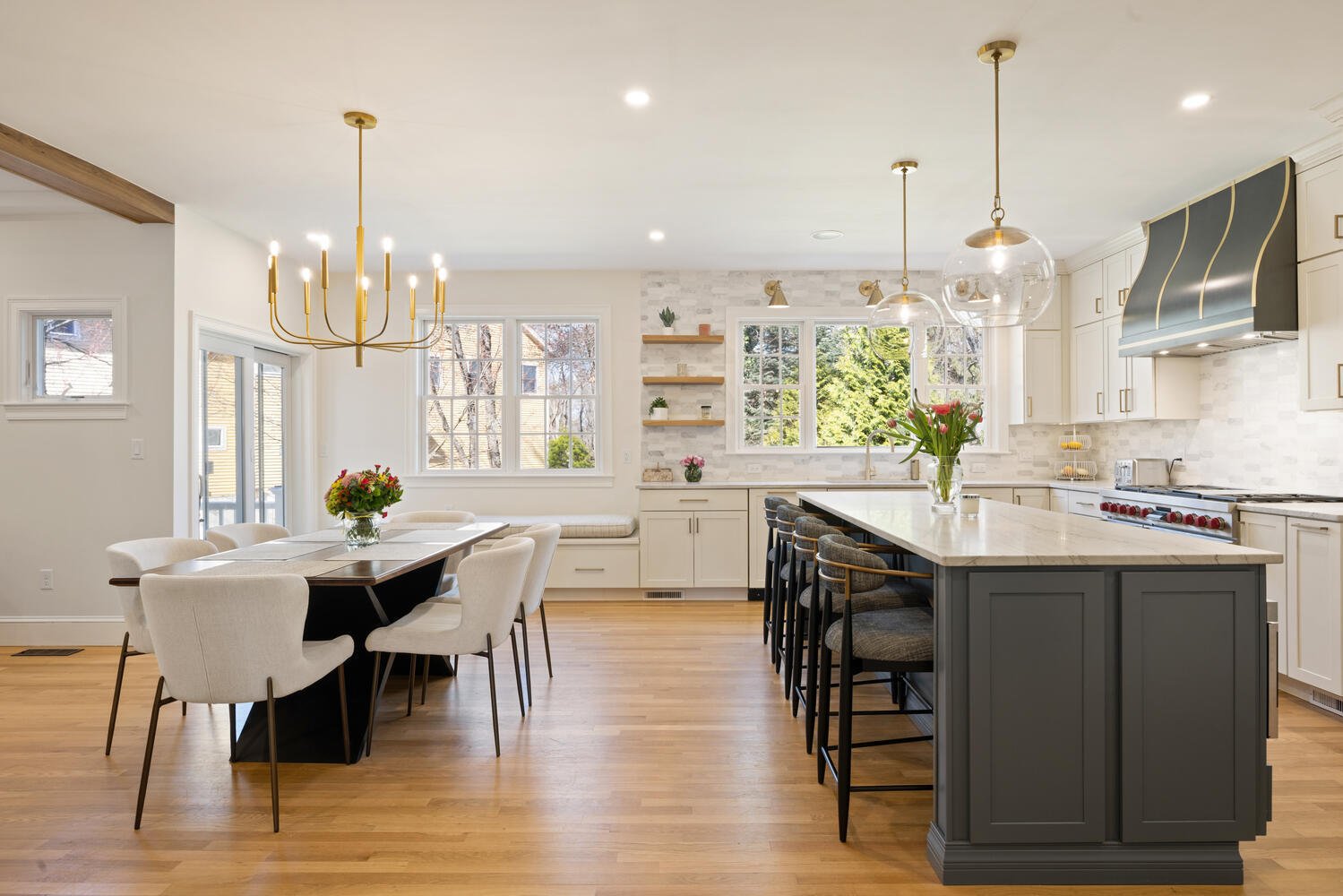 Elegant kitchen and dining addition in Lexington, MA by Pegasus Design-to-Build with large island, pendant lighting, and custom cabinetry