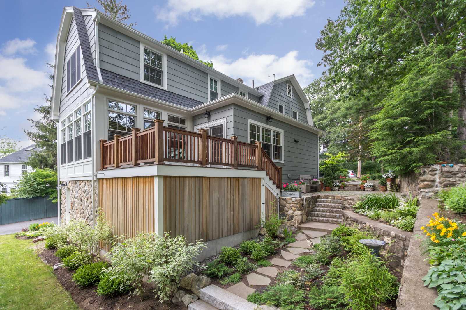 Rear exterior of home addition in Lexington, MA by Pegasus Design-to-Build with deck and landscaped yard-optimized