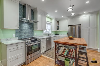 Open white kitchen with butcher-block island, tiled range wall and stainless range in a kitchen addition in Arlington, MA
