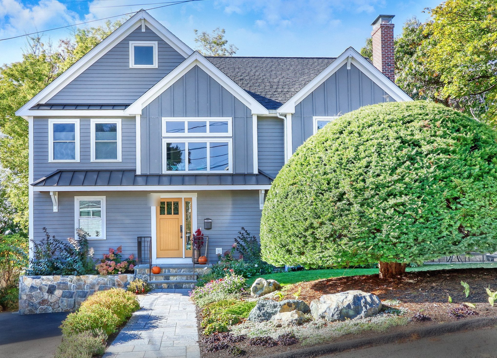 Front of a ranch home in Arlington, MA after a full second-story addition with board-and-batten gables and a metal-roofed entry