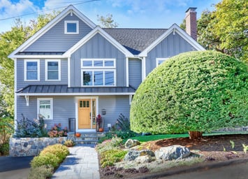 Front of a ranch home in Arlington, MA after a full second-story addition with board-and-batten gables and a metal-roofed entry