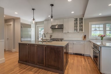Renovated kitchen in Belmont, MA with white cabinets, a dark wood island with marble-look counter, pro range and oak floors