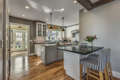 Farmhouse-style kitchen with white shaker cabinets, gray island and peninsula seating in Melrose, MA