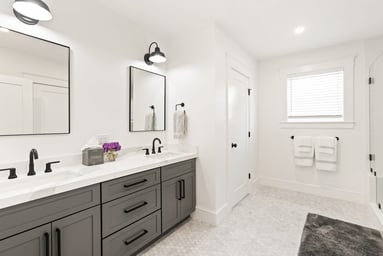 New attic primary bathroom in Wakefield, MA with a gray double vanity, white quartz top, black fixtures and hex marble floor tile