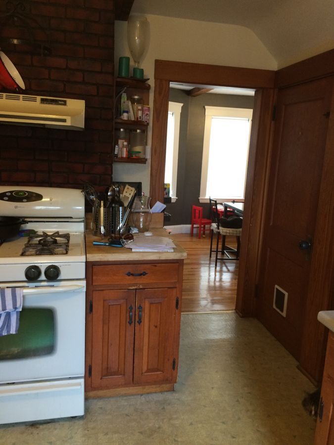 Before: Kitchen: the range against the old brick chimney and the narrow doorway gave way to an open kitchen with a long navy island and seating.
