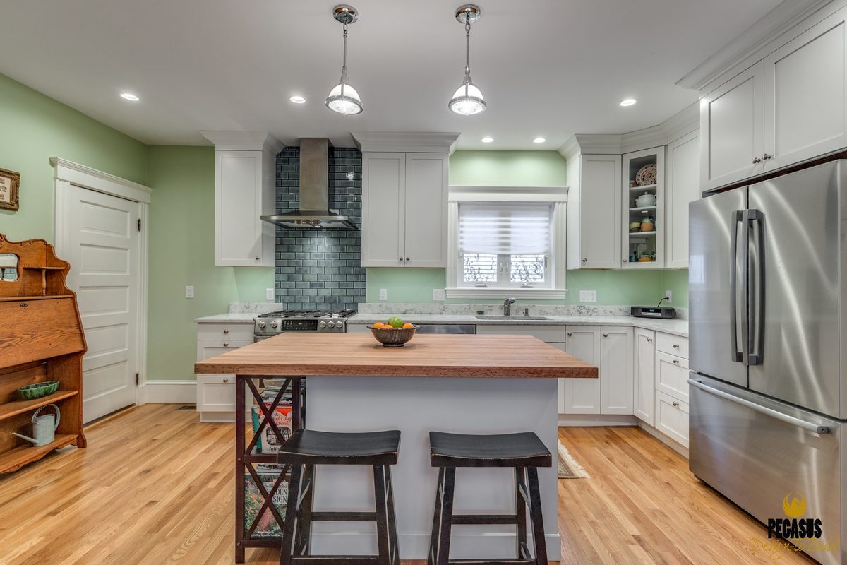 After: Kitchen: a small galley seen through a narrow doorway became an open kitchen with a butcher-block island, a tiled range wall and a window over the sink.
