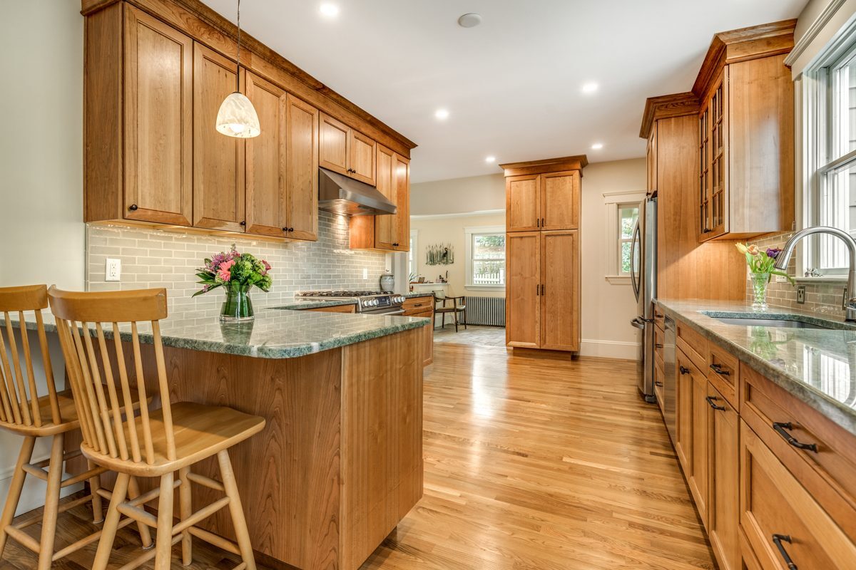 After: Kitchen: maple cabinets, butcher-block tops and terracotta tile gave way to cherry cabinets, green granite and oak floors.