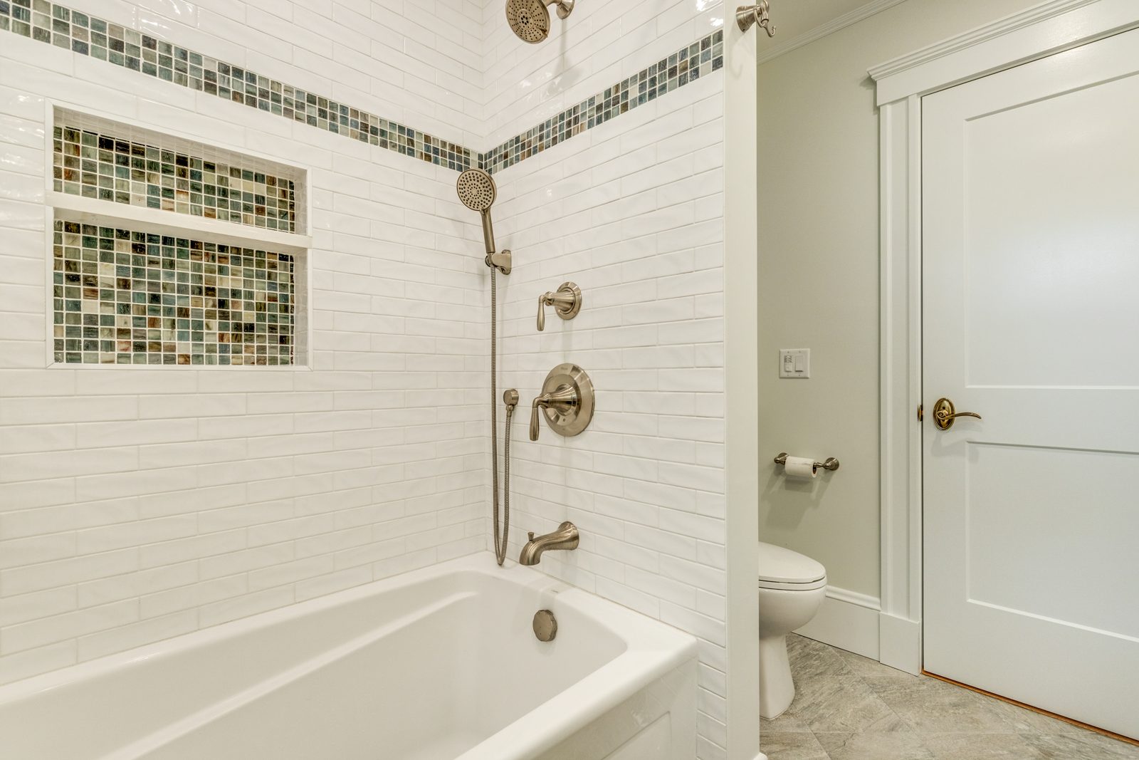 Tub and shower with white subway tile, a glass mosaic band and a built-in niche