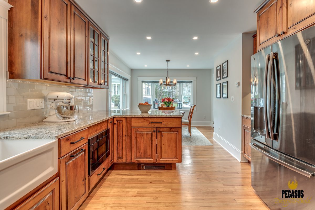 After: Kitchen to dining room: a narrow doorway became a wide-open run of rustic alder cabinets and oak floor straight through to the dining area.