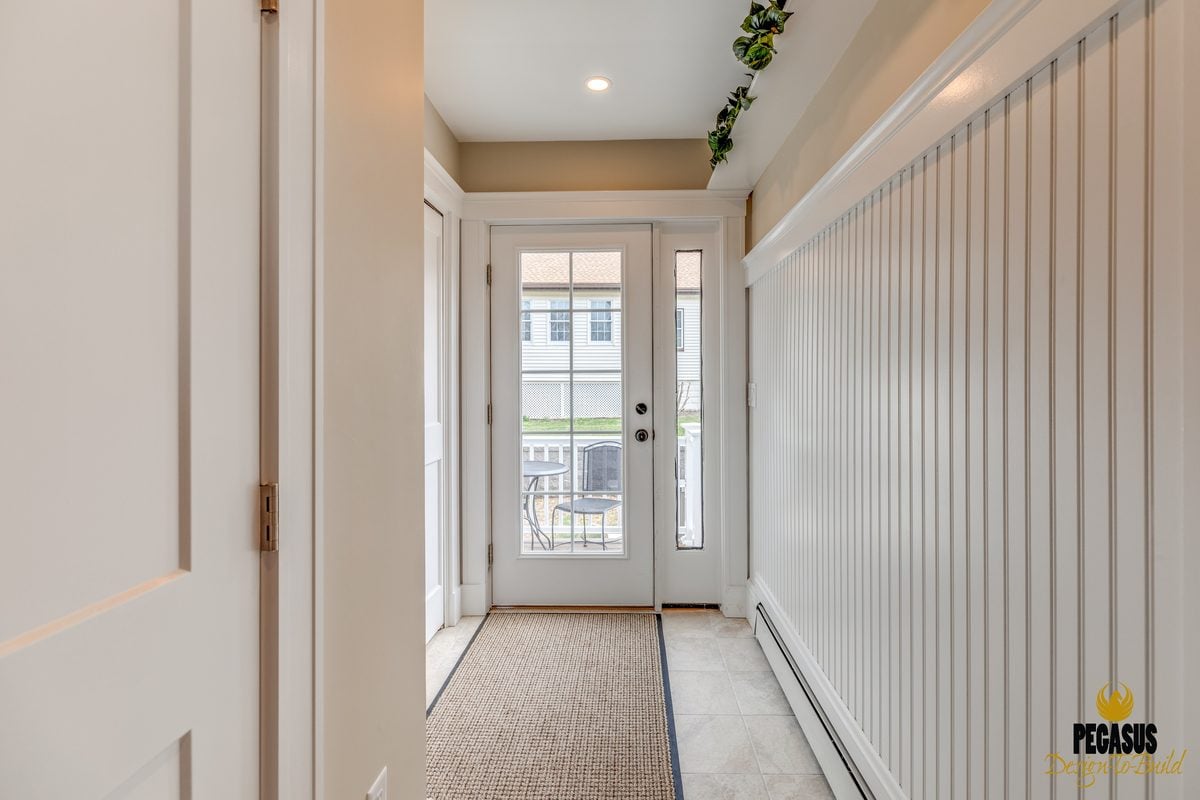 After: Back entry: the cramped back door off the kitchen moved into a new mudroom addition with beadboard walls, a tile floor and a closet.