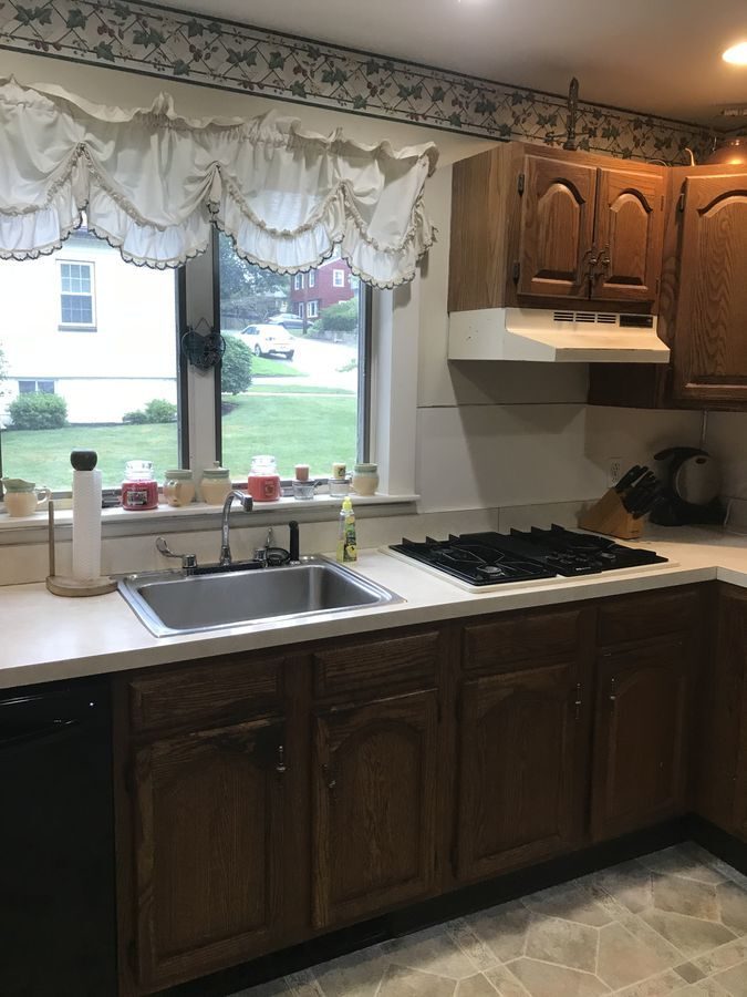 Before: Sink wall: dark oak cabinets, laminate counters and a drop-in cooktop gave way to rustic alder cabinets, granite counters, a fireclay farmhouse sink and a subway tile backsplash.