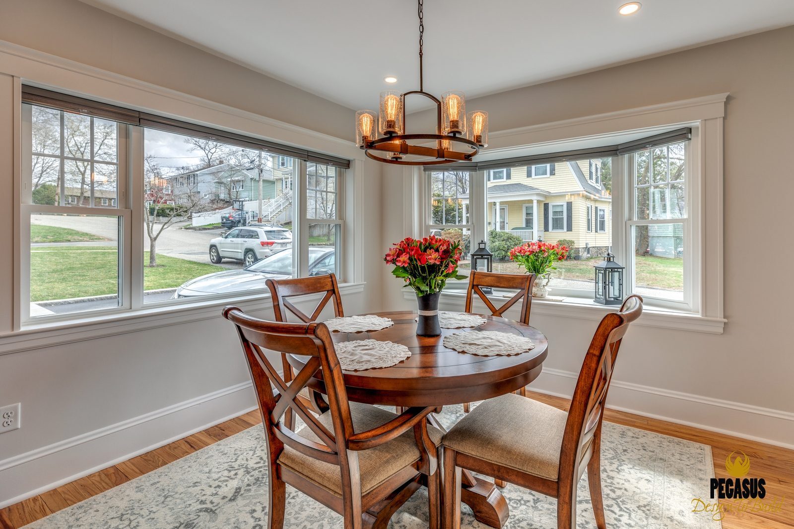 Dining area with bay windows and a round table next to the remodeled kitchen in Arlington, MA