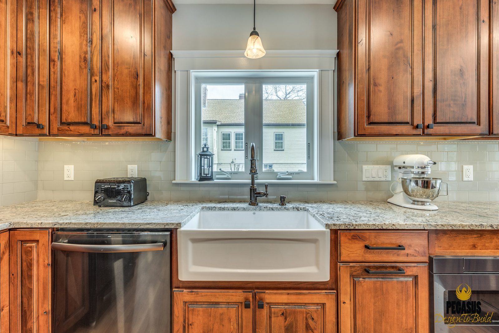 Fireclay farmhouse sink under a window with alder cabinets and subway tile backsplash in Arlington, MA
