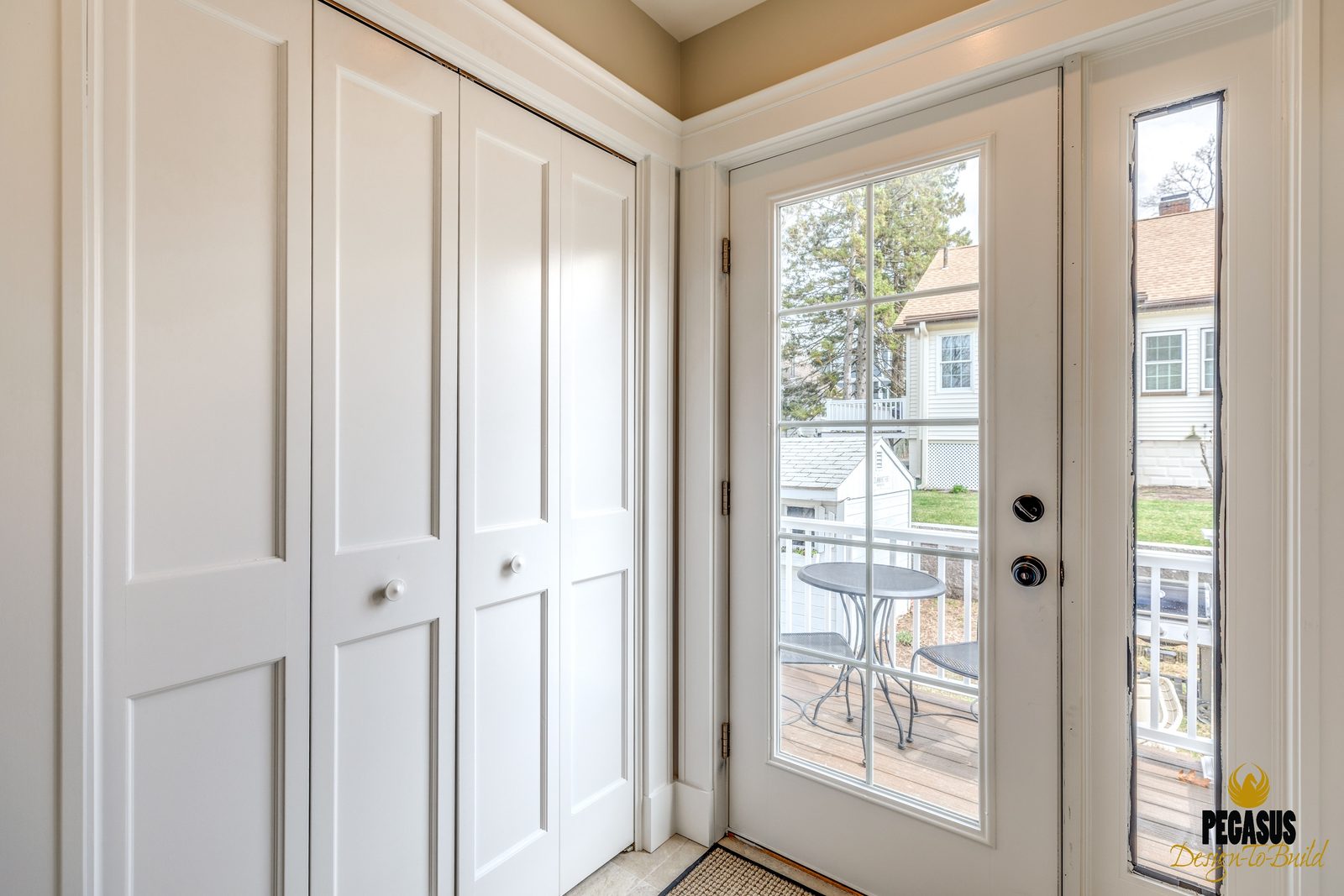 New mudroom with double closet doors and a glass door out to the back deck in Arlington, MA