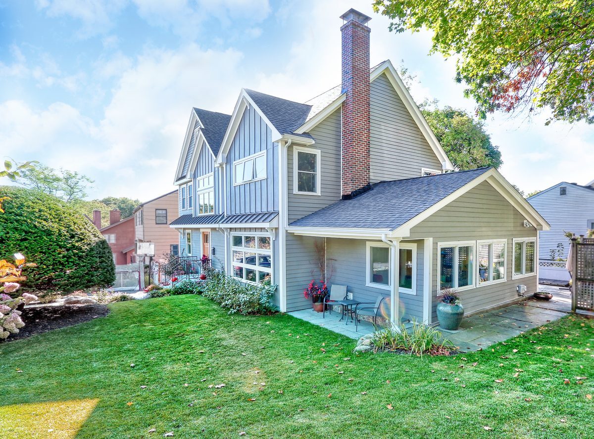 After: Back corner: the one-story family room wing stayed, and the new second story with its gables and transom windows now rises behind it.