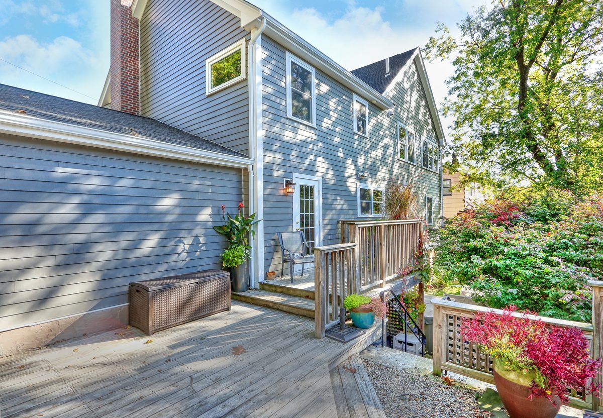 After: Rear deck: the same deck and back door, now under a full second floor with new siding and windows.