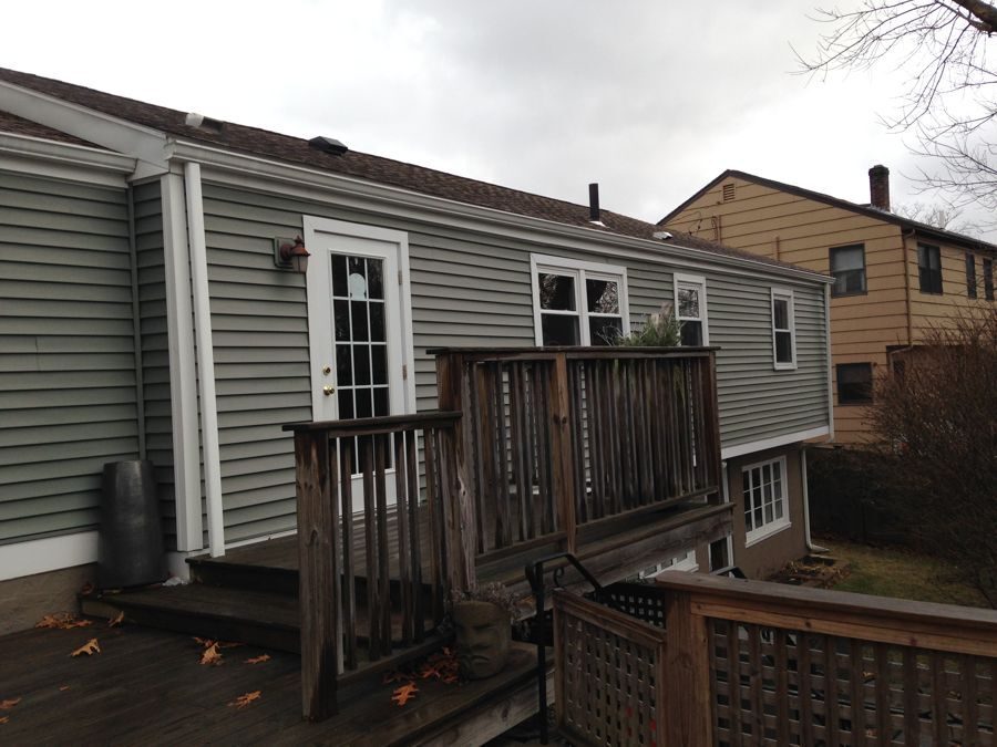 Before: Rear deck: the same deck and back door, now under a full second floor with new siding and windows.