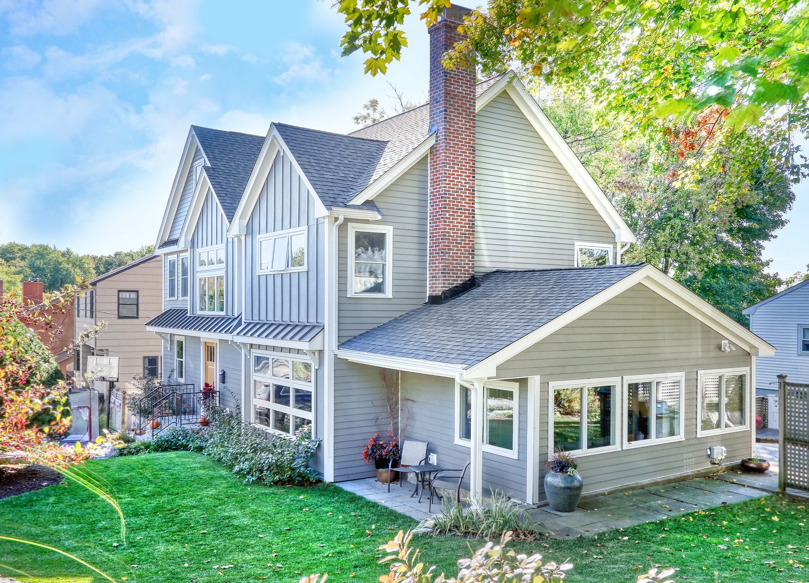 Side and rear view of the two-story addition with gray siding, gables and sunroom in Arlington, MA