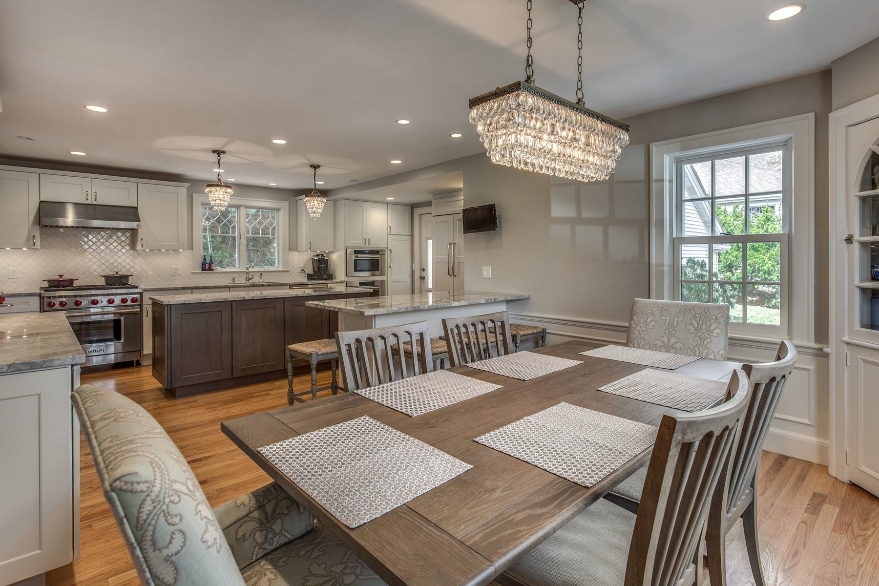 Open dining area looking into the remodeled white and gray kitchen in Belmont, MA