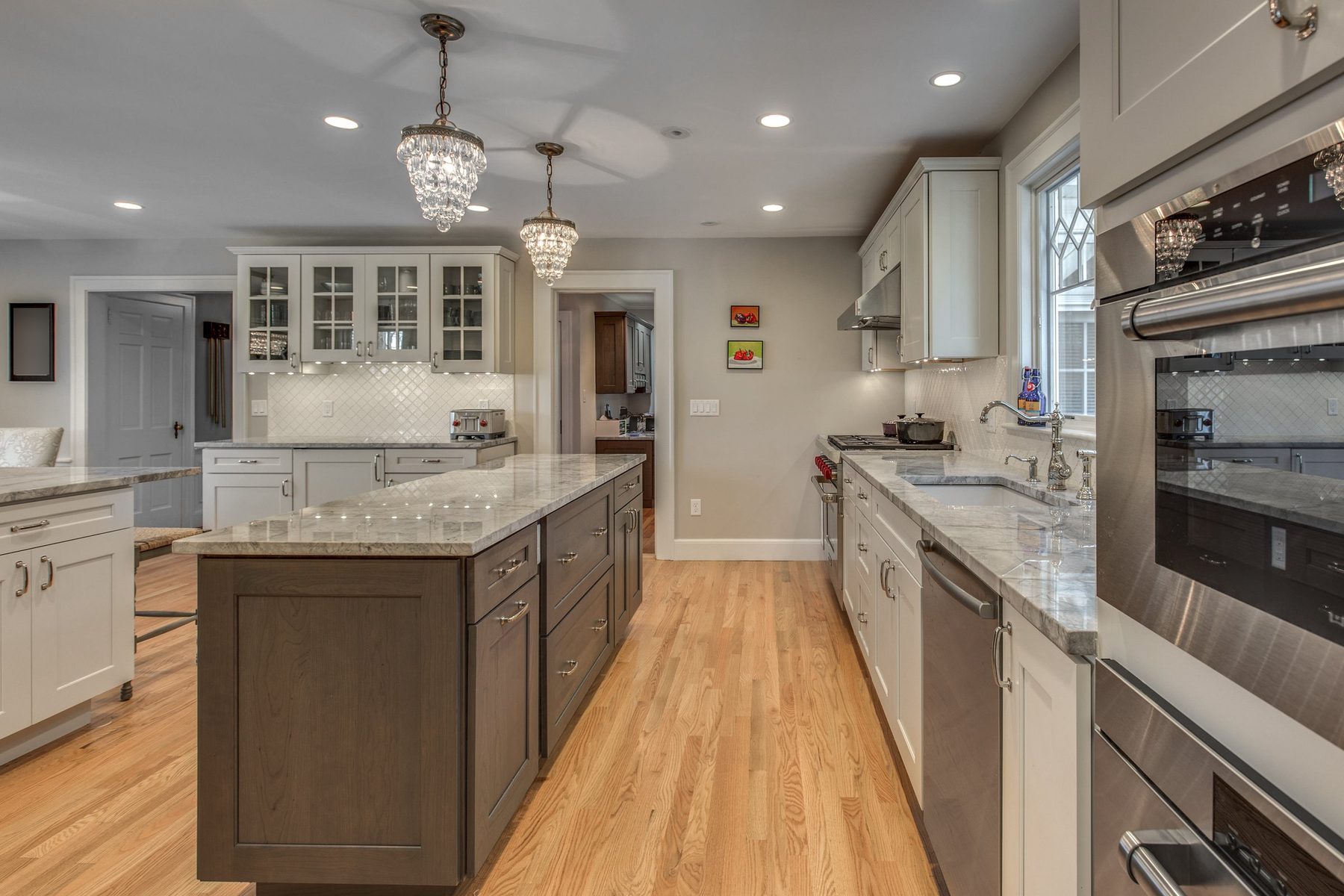 Gray-stained island, sink wall and built-in wall ovens in a remodeled kitchen in Belmont, MA