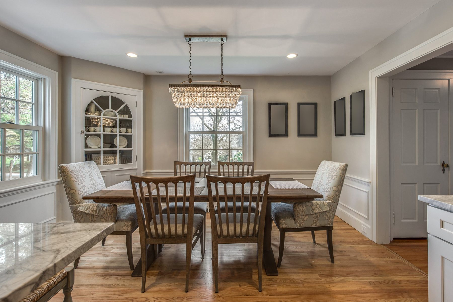 Dining room with original arched corner china cabinet and crystal chandelier in Belmont, MA