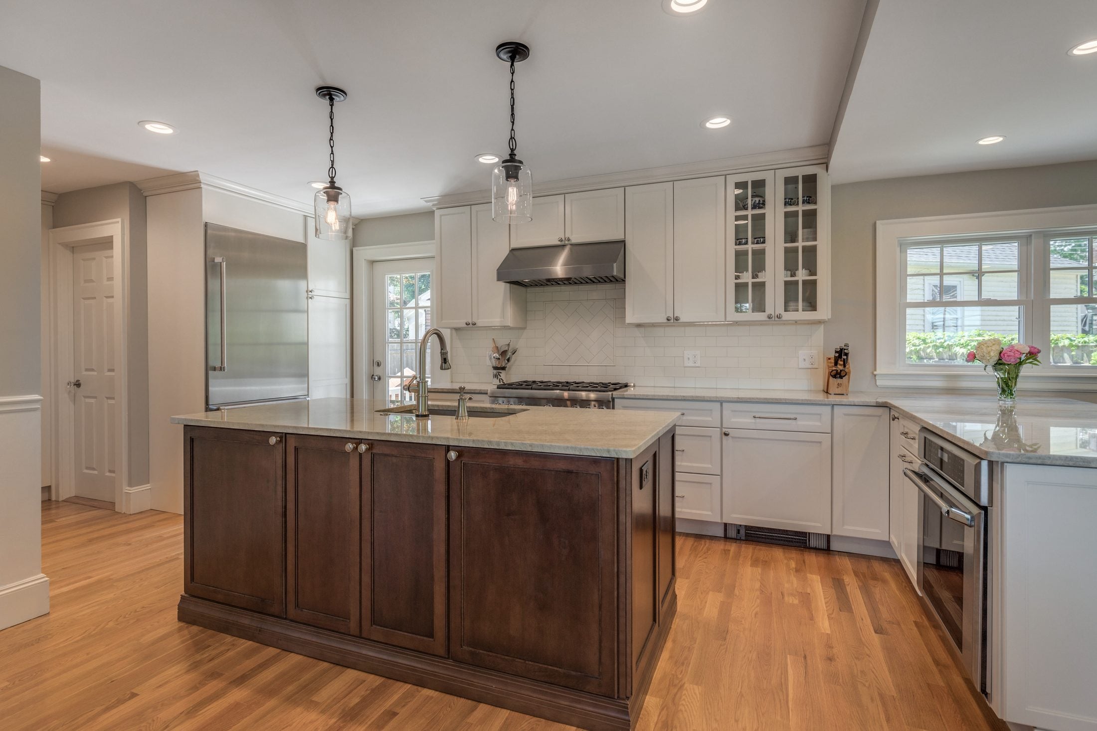 Renovated kitchen in a Belmont, MA home with white cabinets, a dark wood island and oak floors