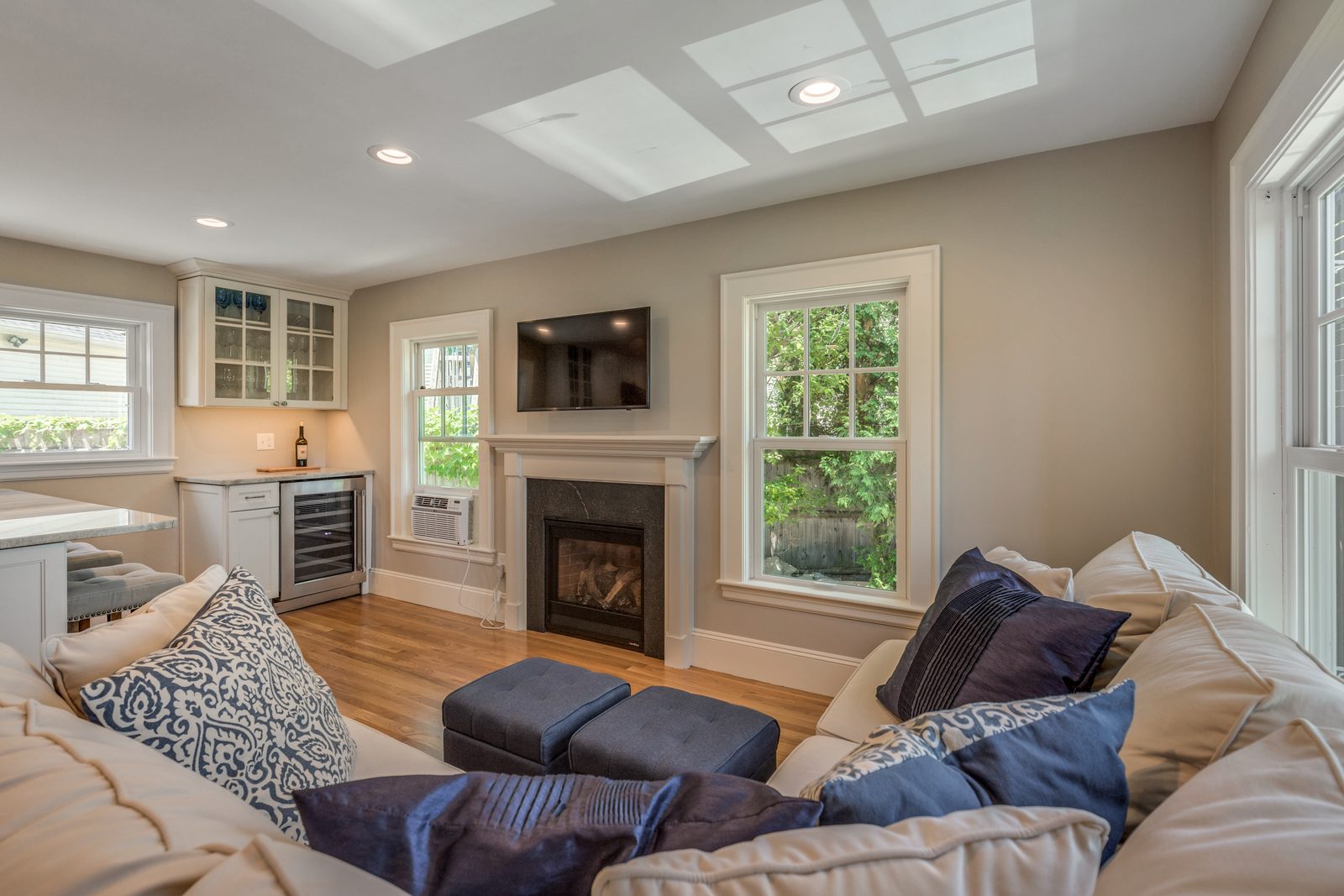 Family room in Belmont, MA with gas fireplace, mounted TV and windows, open to the kitchen
