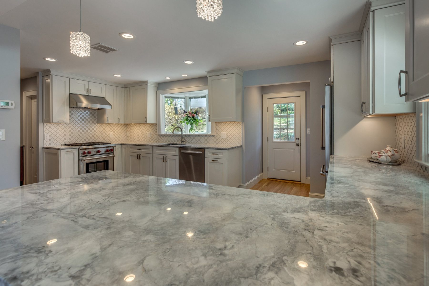 Gray-veined stone peninsula looking toward the range, bay window and back door in Belmont, MA