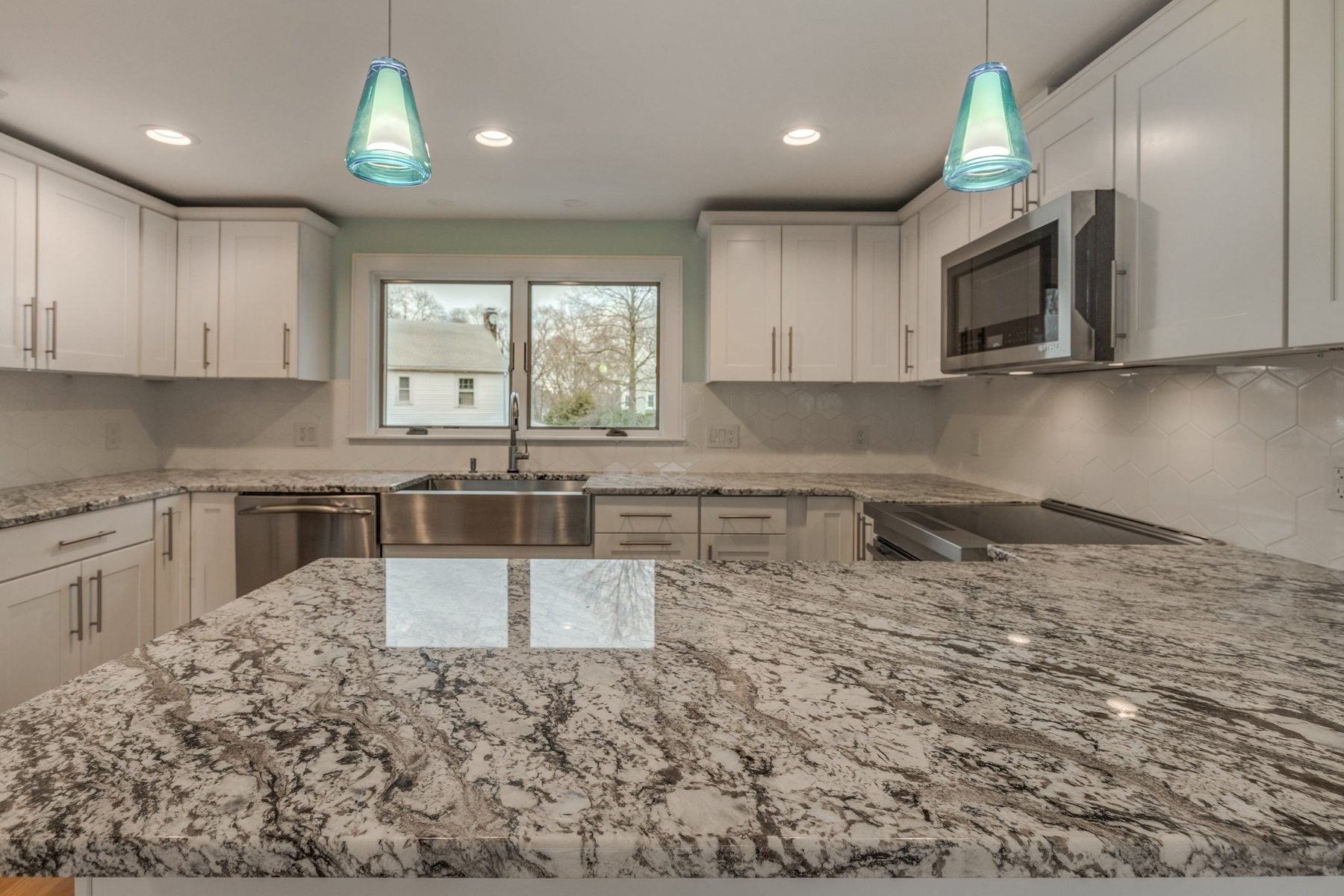 Peninsula facing the sink window and white Shaker cabinets in a Belmont, MA kitchen