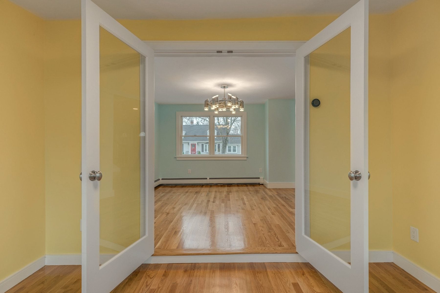 Double glass doors from the sunroom opening into the dining room in Belmont, MA