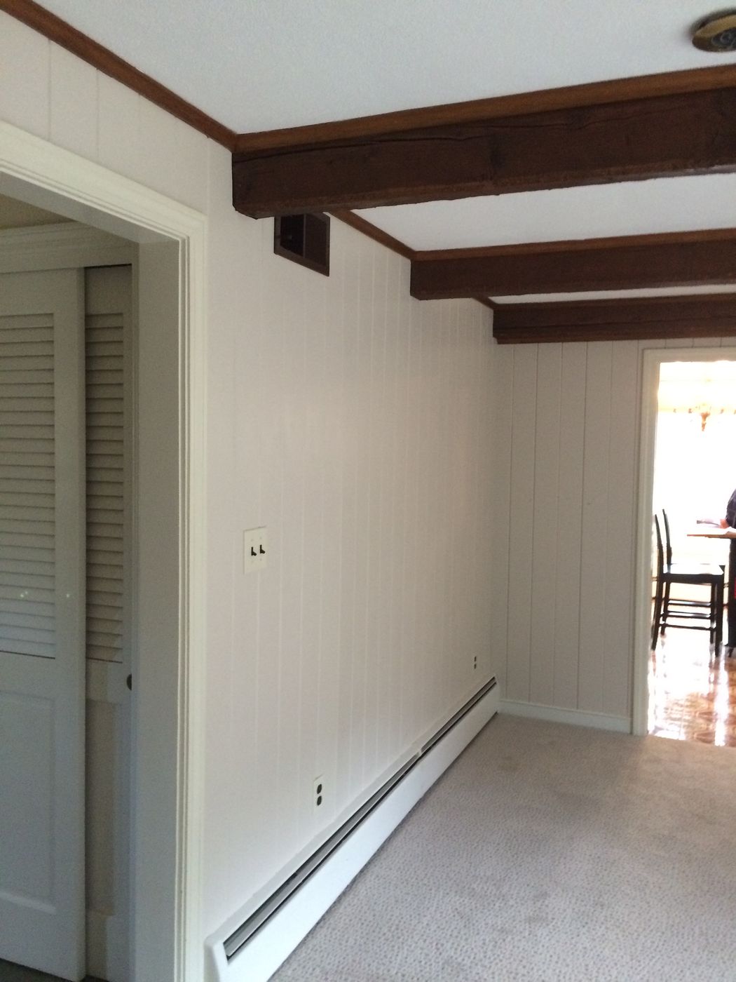 Before: Family room: paneled walls and a single doorway gave way to smooth walls, recessed lights and wide openings to the kitchen and dining room.