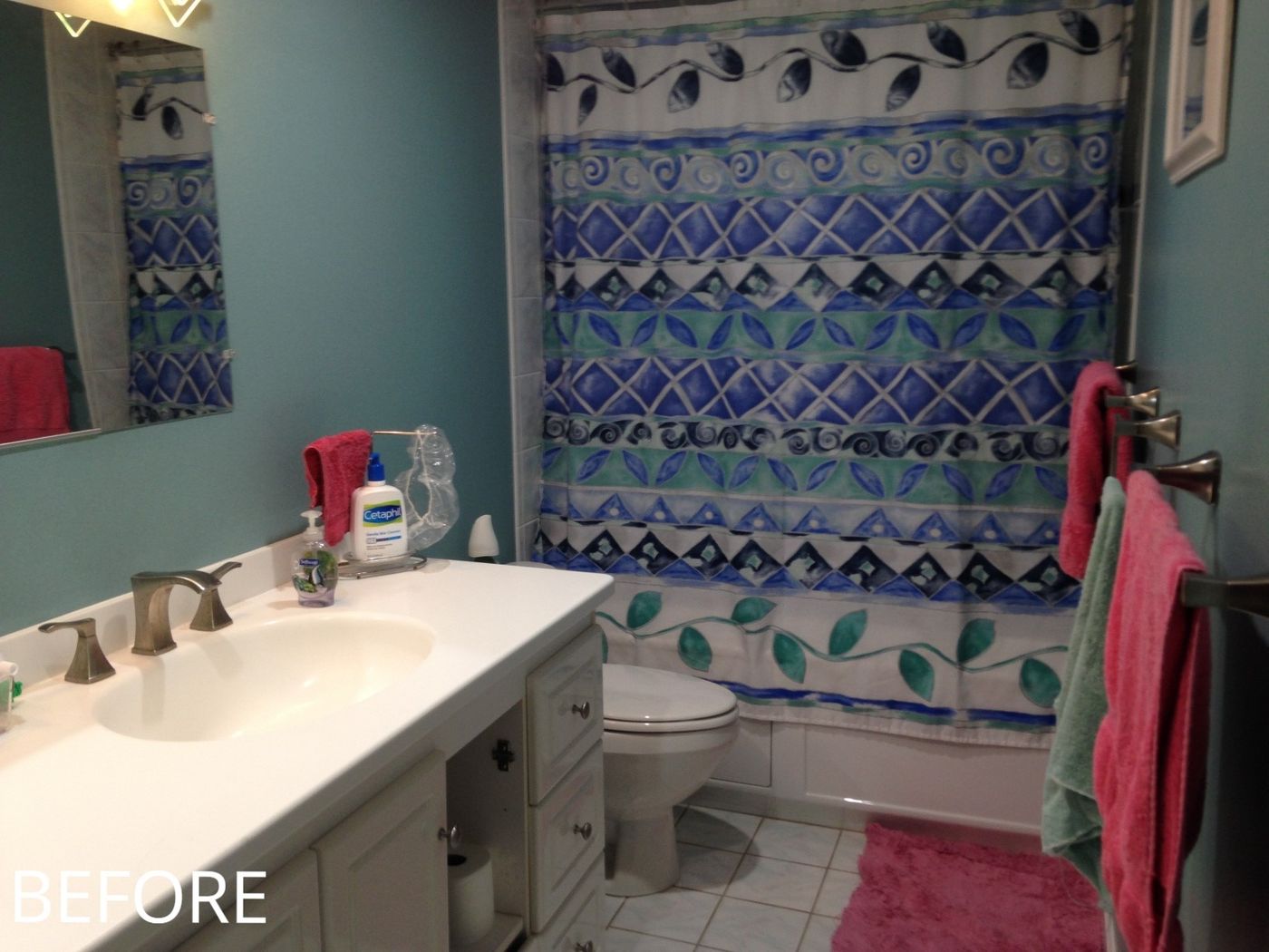 Before: Primary bath: the tub and shower curtain were replaced by a walk-in shower with gray tile, a glass accent band and a sliding glass door.