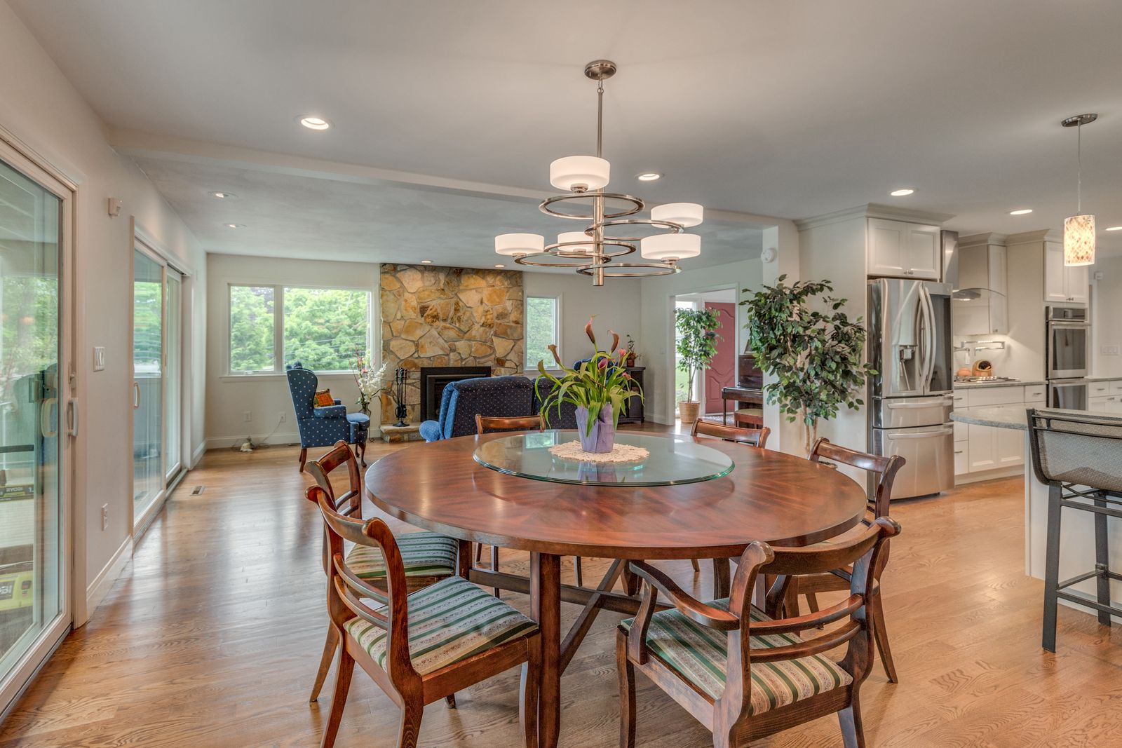 Dining area open to the living room and stone fireplace, with oak floors running through