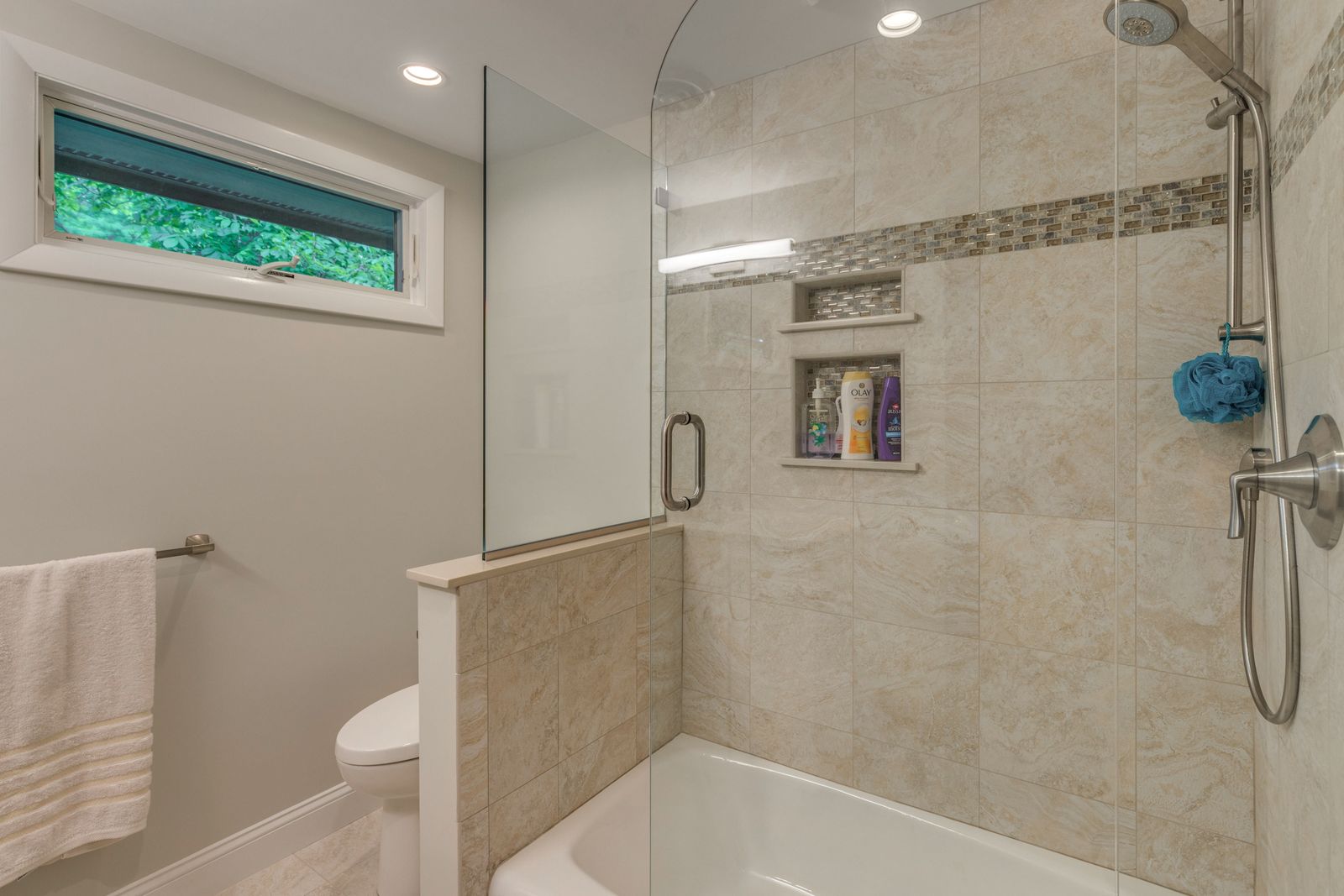Tiled tub and shower with a glass panel, a glass mosaic band and recessed niches