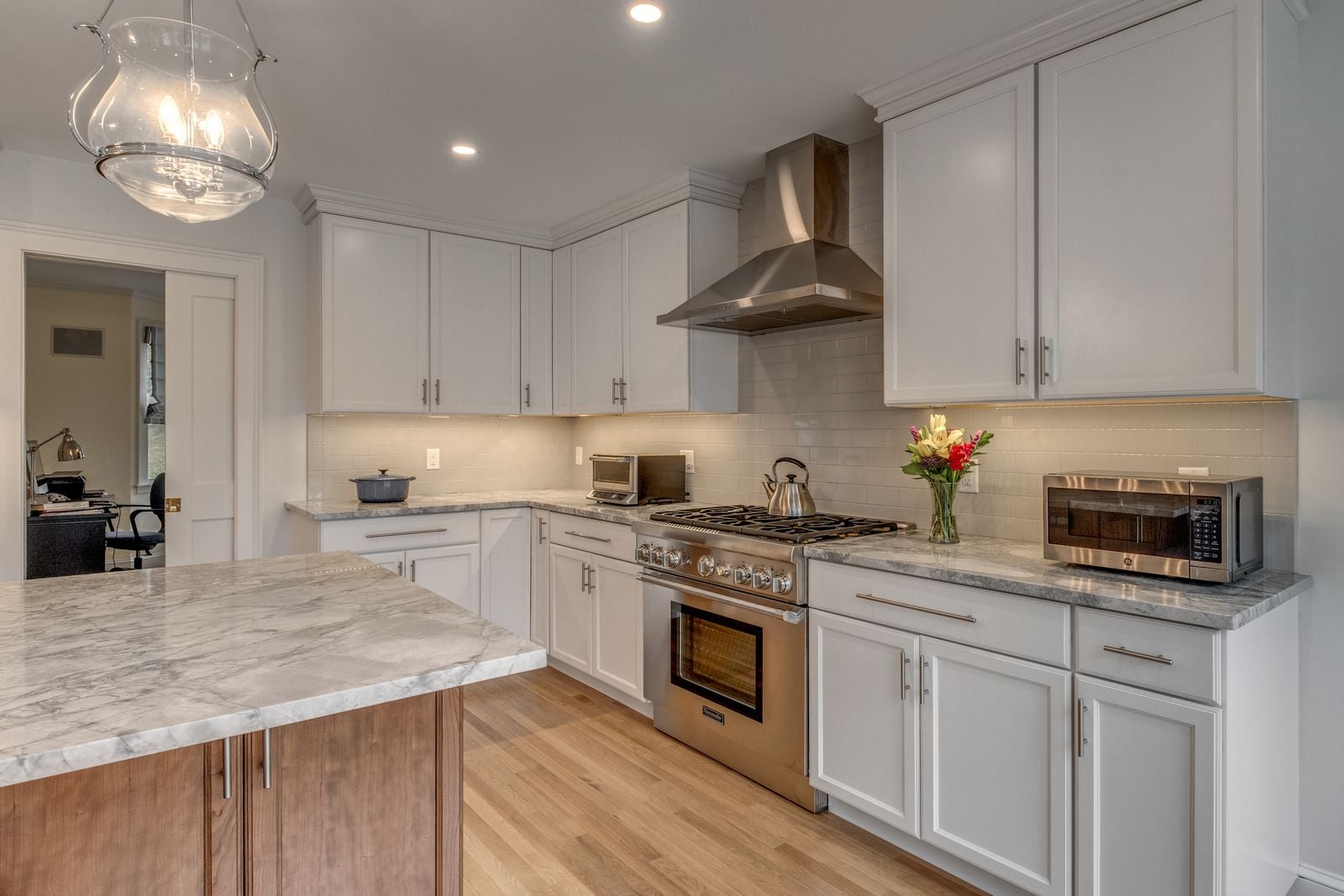 Range wall with a stainless chimney hood, white cabinets and a tile backsplash
