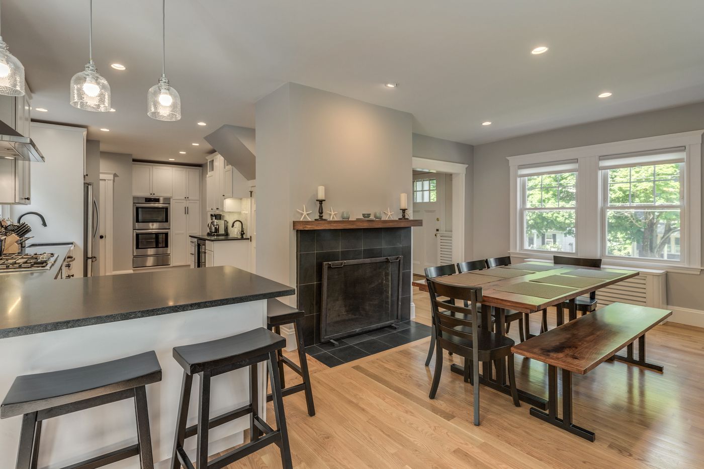 After: Fireplace: the painted brick surround was refaced in dark slate tile with a wood mantel, now anchoring a dining area open to the kitchen.