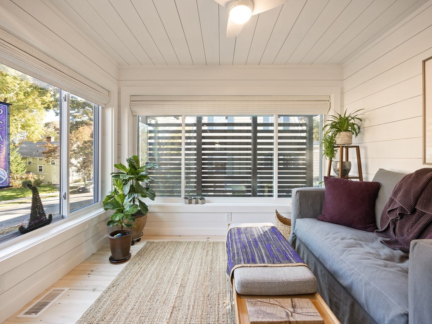 After: Side porch: the open screen porch was enclosed as a year-round sunroom with shiplap walls and ceiling and wide windows.
