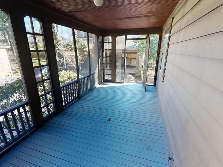 Before: Side porch: the open screen porch was enclosed as a year-round sunroom with shiplap walls and ceiling and wide windows.