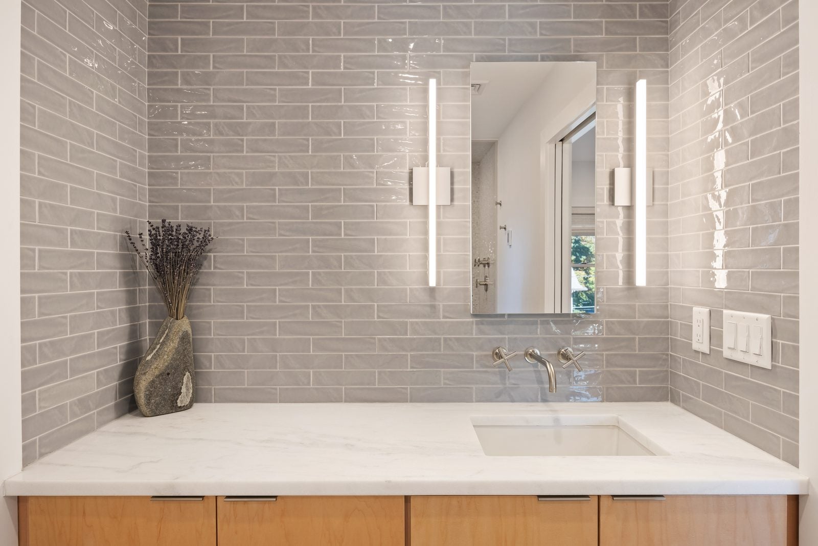 Bath vanity with maple drawers, marble top, wall-mounted faucet and glossy gray brick tile
