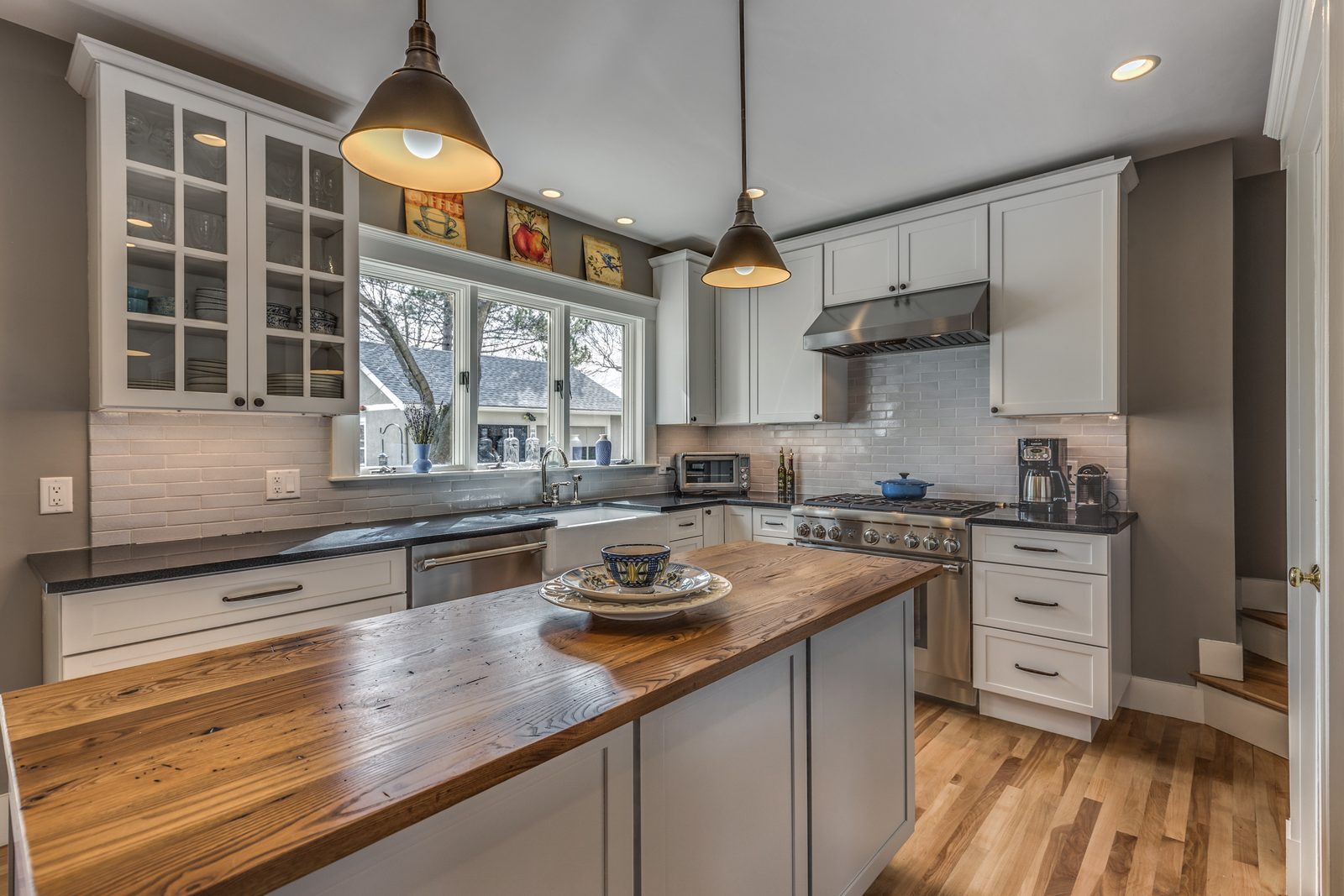 Reclaimed wood island top with white shaker cabinets, subway tile backsplash and pro-style range